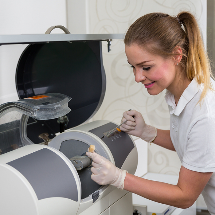 Dentist placing a small ceramic block into a same day dental crown machine