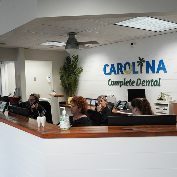 Four dental team members sitting behind the front desk