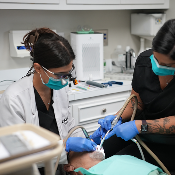Two dental professionals performing gum disease treatment on a patient