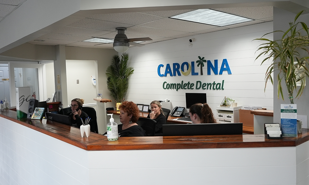 Four dental team members sitting at the front desk