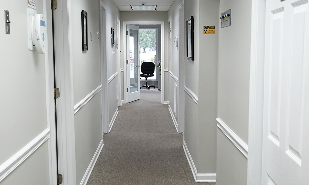 Hallway painted white and leading to dental treatment areas