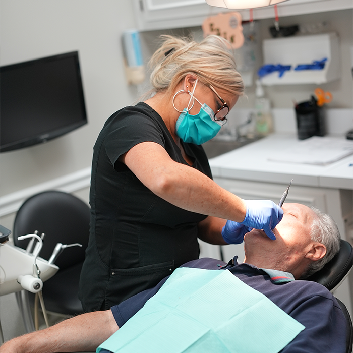 Dental team member giving a patient a teeth cleaning