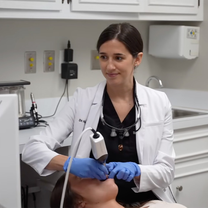 Two smiling dental team members sitting behind the front desk