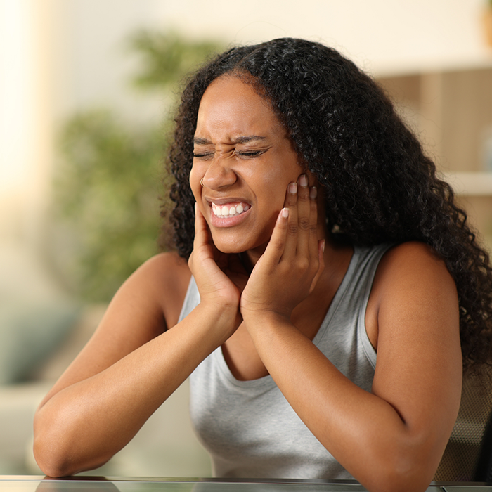 Woman holding both sides of her jaw and wincing in pain