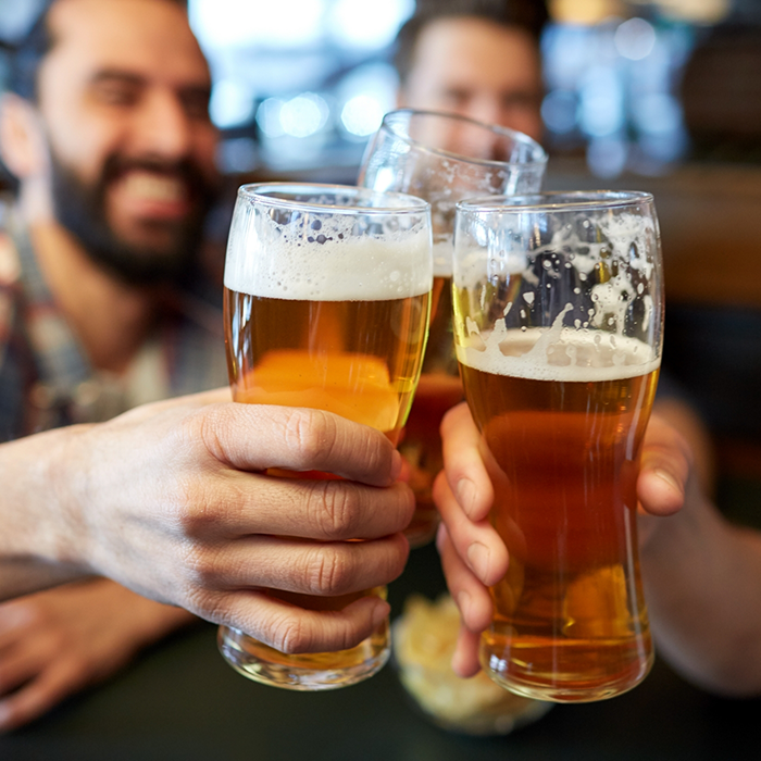 Three people at a restaurant toasting their glasses of beer