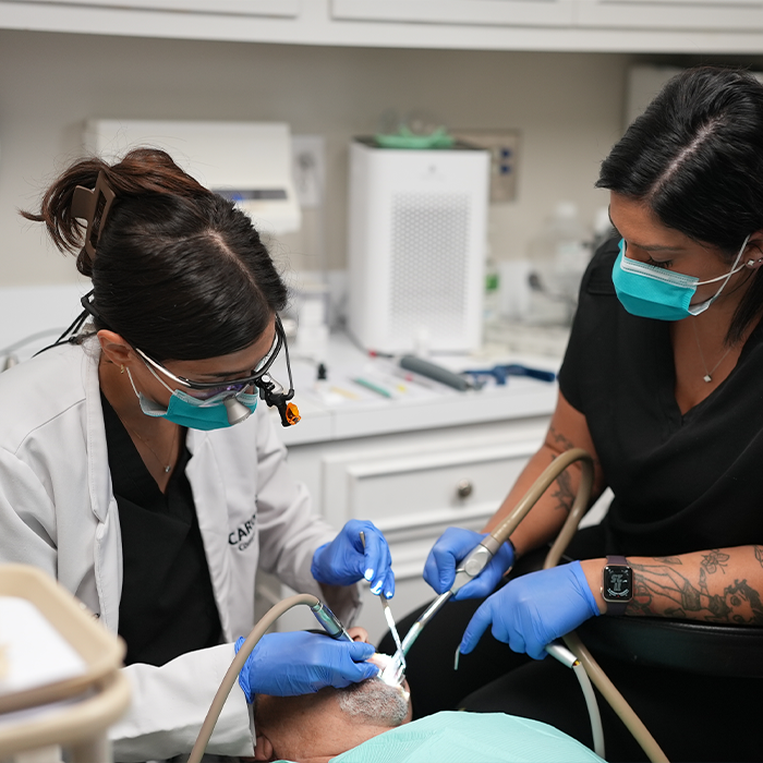 Dentist and assistant performing wisdom tooth extractions on a Goose Creek dental patient